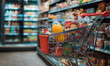 © ValNik Creations - Supermarket grocery cart. Shopping cart filled with food and drinks and supermarket shelves in the background, grocery shopping concept.
