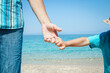 © Kostia - A hands of a happy parent and child by the sea in nature travel
