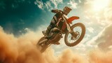 Fototapeta  - The racer on a motorcycle participates in trains on motocross in flight, jumps and takes off on a springboard against the sky. The smoke and dust fly from under 