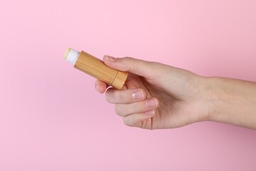 Wall Mural - Woman with lip balm on pink background, closeup