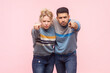 © khosrork - Portrait of angry irritated woman and man standing pointing together at camera arguingg with somebody expressing hate. Indoor studio shot isolated on light pink background.