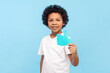 © khosrork - Portrait of cheerful positive little boy with curly hair showing paper thumb up internet trends asking to appreciate his post in kid's blog. Indoor studio shot isolated on blue background.