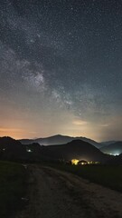 Wall Mural - vertical panorama of starry night sky with milky way galaxy stars over countryside landscape astrono