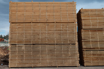 Stacks of boards, board flooring in a sawmill. Warehouse for cutting boards in a sawmill outdoors. Stack of wooden blanks construction material wood timber. Industry.