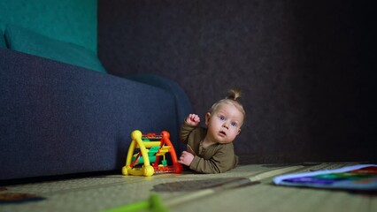 Sticker - Caucasian infant with blond hair lies on the floor looking up with surprise. Little kid with a bright toy.