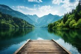 Fototapeta  - Breathtaking view from wooden dock of serene lake nestled amidst vibrant greenery and towering mountains.