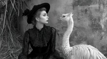  A Black And White Photo Of A Woman In A Hat And An Ostrich In Front Of A Wall.