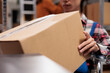 Warehouse worker using wheelchair while holding cardboard box in hands. Storehouse order handler preparing product for dispatching, taking packed parcel ready for shipment close up