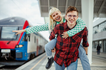 Wall Mural - Portrait of an urban couple having piggyback ride at train station.