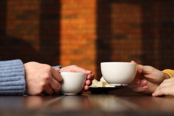 Poster - Women having coffee break at wooden table in cafe, closeup