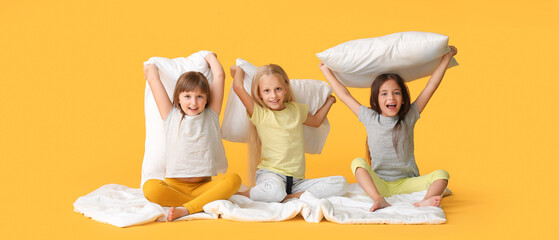 Wall Mural - Happy little girls with pillows on yellow background