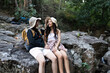 © itchaznong - Lesbian couple relaxing together on rock at a hiking trail While traveling together on a hiking trail