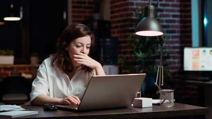 Poster - Weary accountant struggling to remain awake at workspace desk while inputting data on laptop, panning shot. Close up of exhausted businesswoman yawning in office while working overnight, camera B