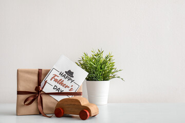 Poster - Card for Father's Day with gift, toy car and houseplant on table near light wall