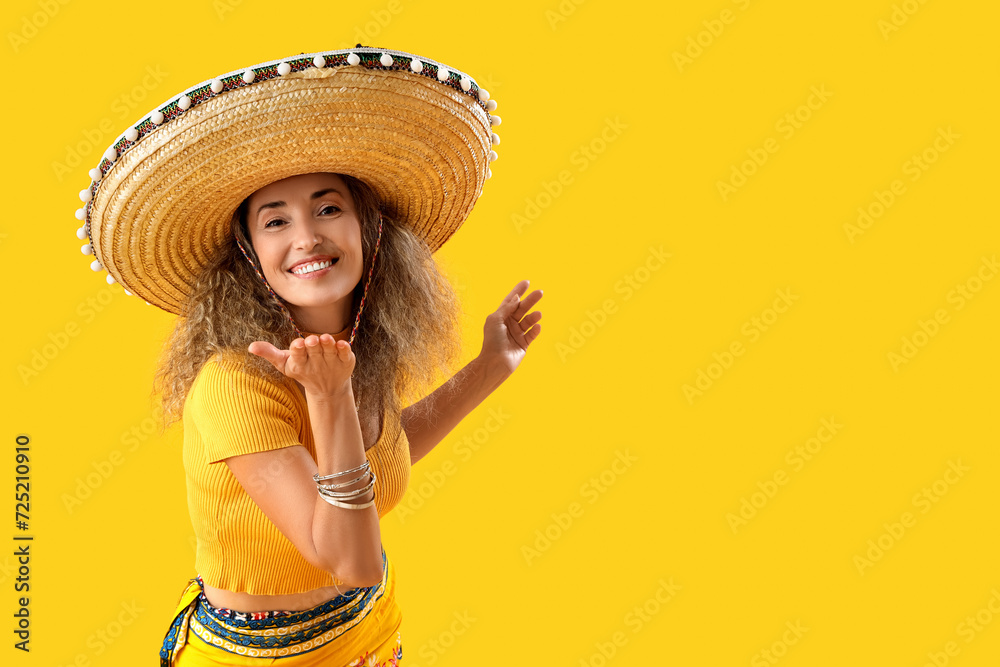 Mature woman in sombrero hat on yellow background. Mexico's Day of the Dead (El Dia de Muertos) celebration