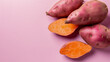 Whole and halved sweet potatoes on a pink background with a place for text, highlighting a healthy food concept