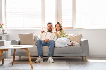 Canvas Print - Happy couple in love sitting on sofa at home