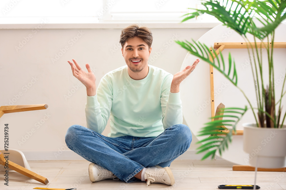 Young man assembling furniture in kitchen