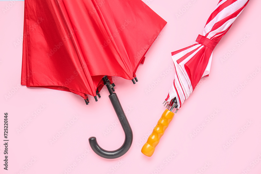 Different stylish umbrellas on pink background