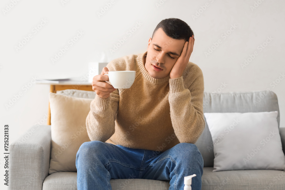 Ill young man with cup of tea video chatting at home