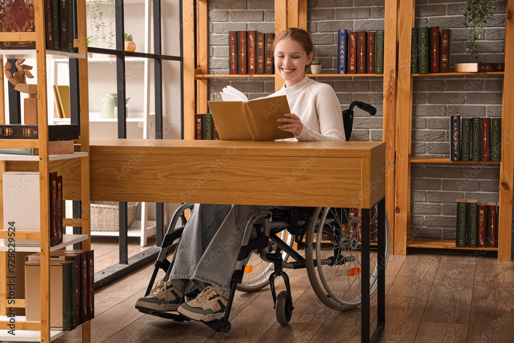 Young redhead woman in wheelchair reading book at library