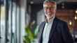 © Postproduction - Confident mature businessman smiling in modern office setting. Professional leadership.