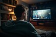 Back view image of cute boy watching streaming service and pointing at the TV screen. guy looking at the screen, nature, home environment
