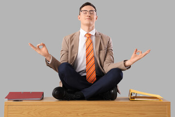 Sticker - Funny businessman meditating on table against light background