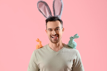 Poster - Happy young man in bunny ears with Easter rabbits on pink background