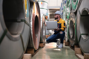 Wall Mural - Industrial engineer in safety helmet uniform jacket working in heavy steel engineering factory. Technician manager worker inspector using laptop in metalwork product manufacturing facility workplace