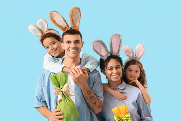 Wall Mural - Happy family in bunny ears with Easter gift eggs hugging on blue background