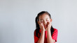portrait of little asian girl tired, lethargic, strain, bored, bad mood concept. studio shot with light color background. pulling funny faces using their hands to pull down on their cheeks