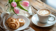 Coffee cup and pastries with tulips on wooden table