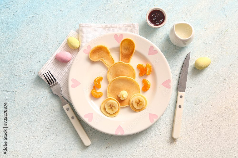 Funny Easter bunny pancakes with banana and painted eggs on light blue background