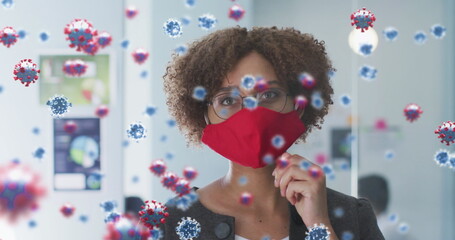 Poster - Image of covid 19 cells over woman in office wearing face mask