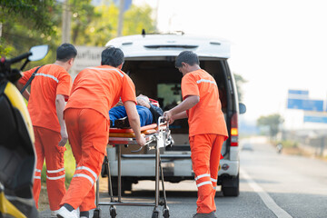 The paramedic  is assisting an injured man in an emergency situation on the road.