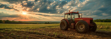 Sunset Over Farmland With Red Tractor. A Serene Sunset View Over A Farm Field, With A Red Tractor Standing Prominently In The Foreground.