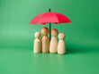 A wooden peg doll family cover by red umbrella