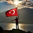 A man holding Turkish Flag top of the mountain 