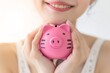 豚の貯金箱を持つ日本人女性（貯金・投資・背景なし）