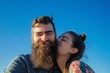 © primopiano - daylight shot: smiling woman kissing bearded mans cheek, blue sky backdrop