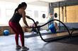 © Wavebreak Media - Side view of dedicated caucasian young woman exercising with battle ropes in health club, copy space