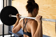 © Wavebreak Media - Rear view of caucasian young woman lifting barbell while standing in health club, copy space