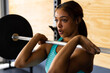 © Wavebreak Media - Closeup of dedicated biracial young woman lifting barbell confidently in health club, copy space
