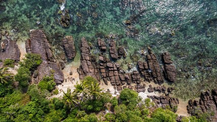 Wall Mural - Aerial view of a rocky tropical beach with clear turquoise waters, lush greenery, and distinctive geological formations
