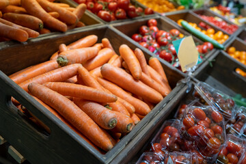 Wall Mural - Carrots in a wooden box in the fruit and vegetable section of a grocery supermarket. Sale of carrots, selective focus. Vegetables in a supermarket close-up