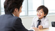 © Robert Kneschke - Young Boy in Suit Smiling at Adult in Business Meeting