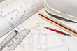 © Wirestock - Background of architecture plans, hard hat and architect tools on table