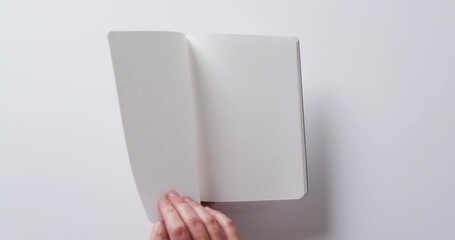 Poster - Close up of hand leafing through book with copy space on white background in slow motion