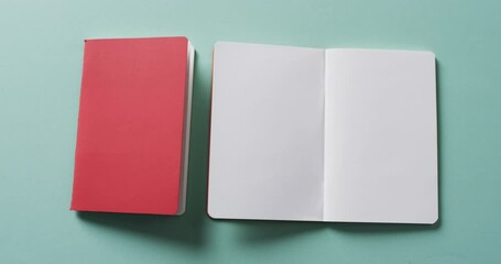 Sticker - Close up of open blank book and closed red book with copy space on green background in slow motion